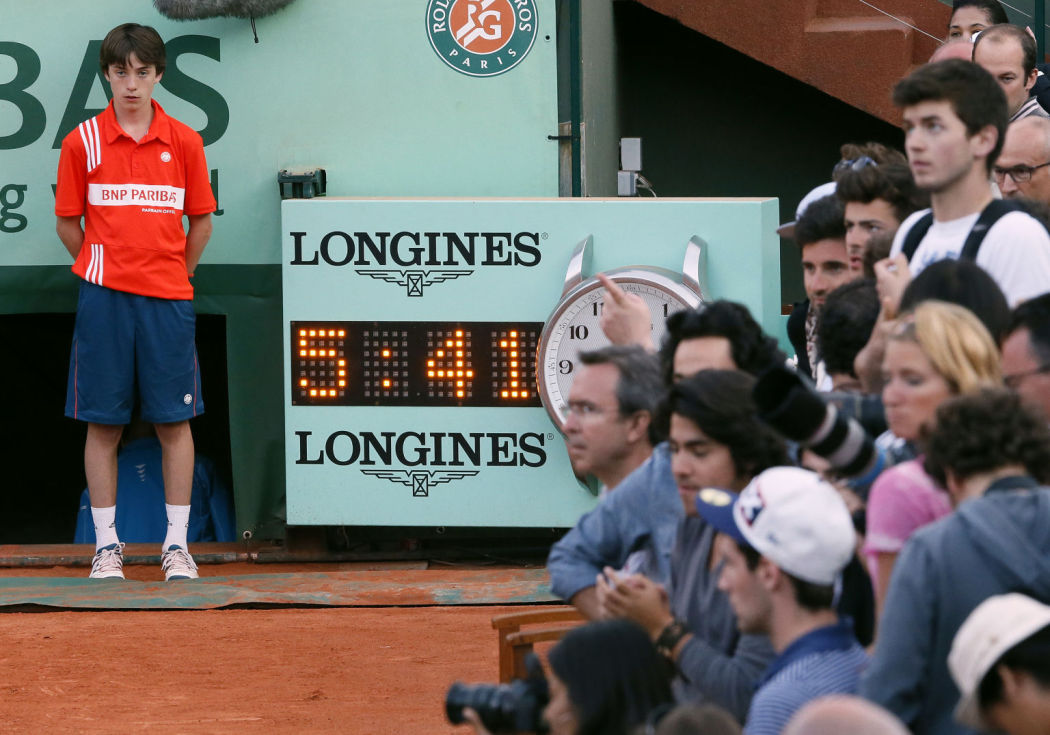 A ball boy stands near a clock as France