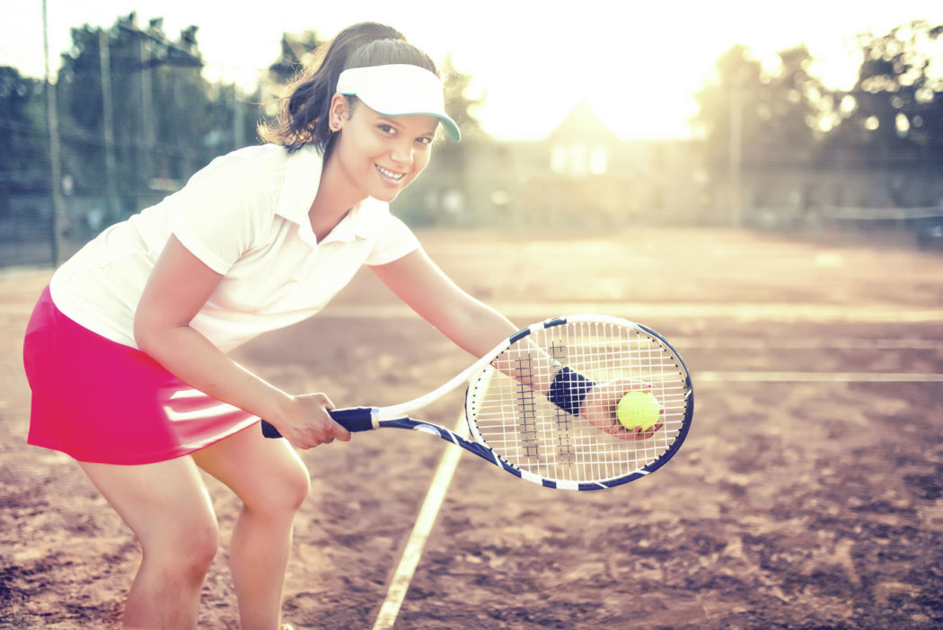 Portrait of beautiful woman on tennis court with athletic wear