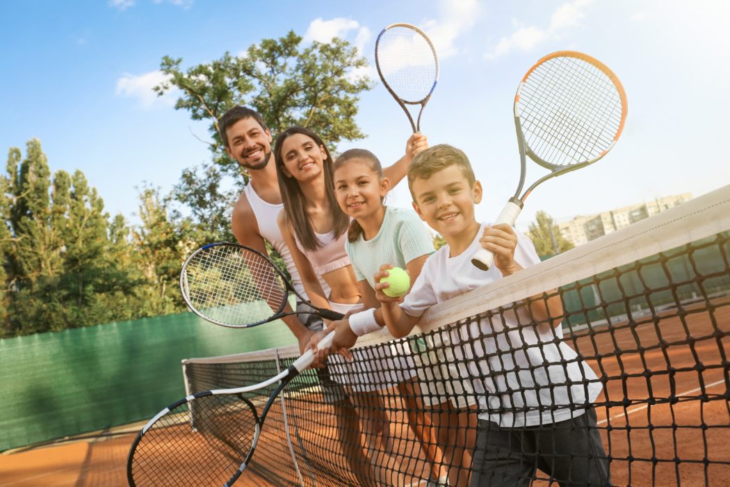 Happy,Family,With,Tennis,Rackets,On,Court,Outdoors