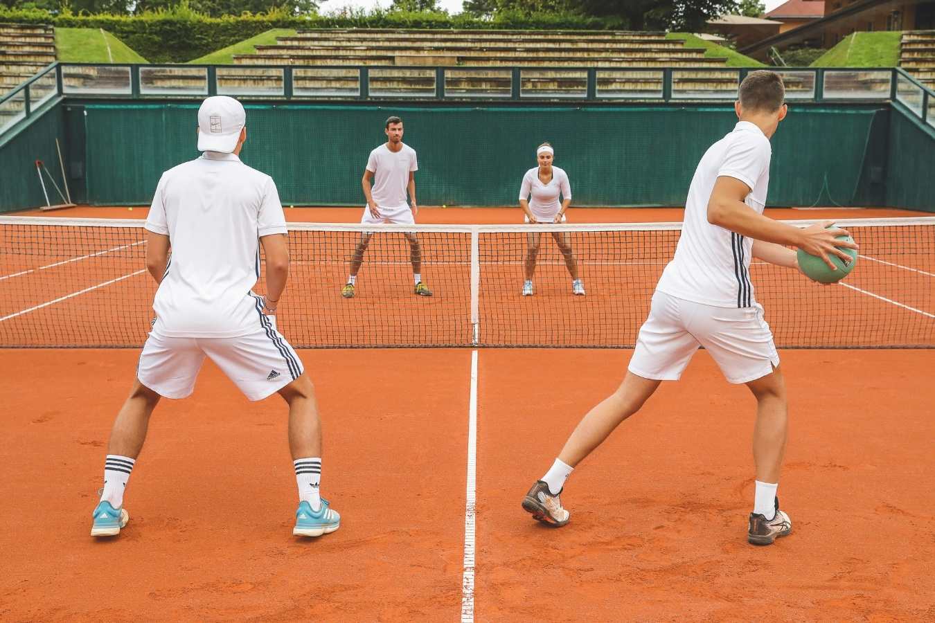 Vier Tennisspieler werfen einen Medizinball übers Netz
