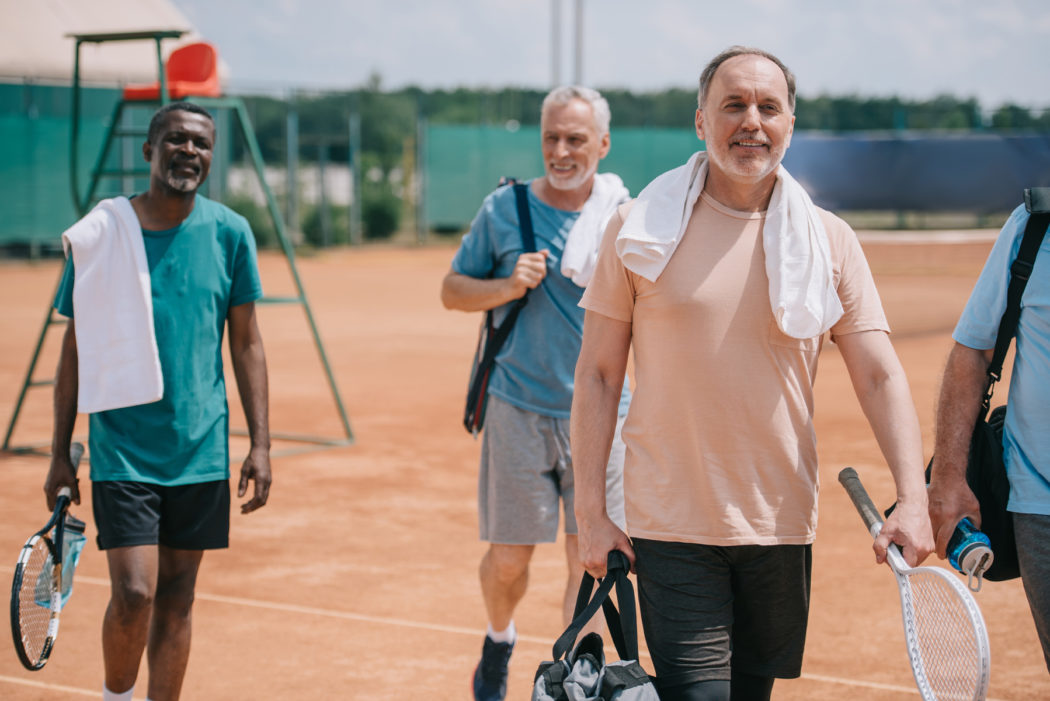 Selective,Focus,Of,Multiracial,Elderly,Friends,With,Tennis,Equipment,Walking